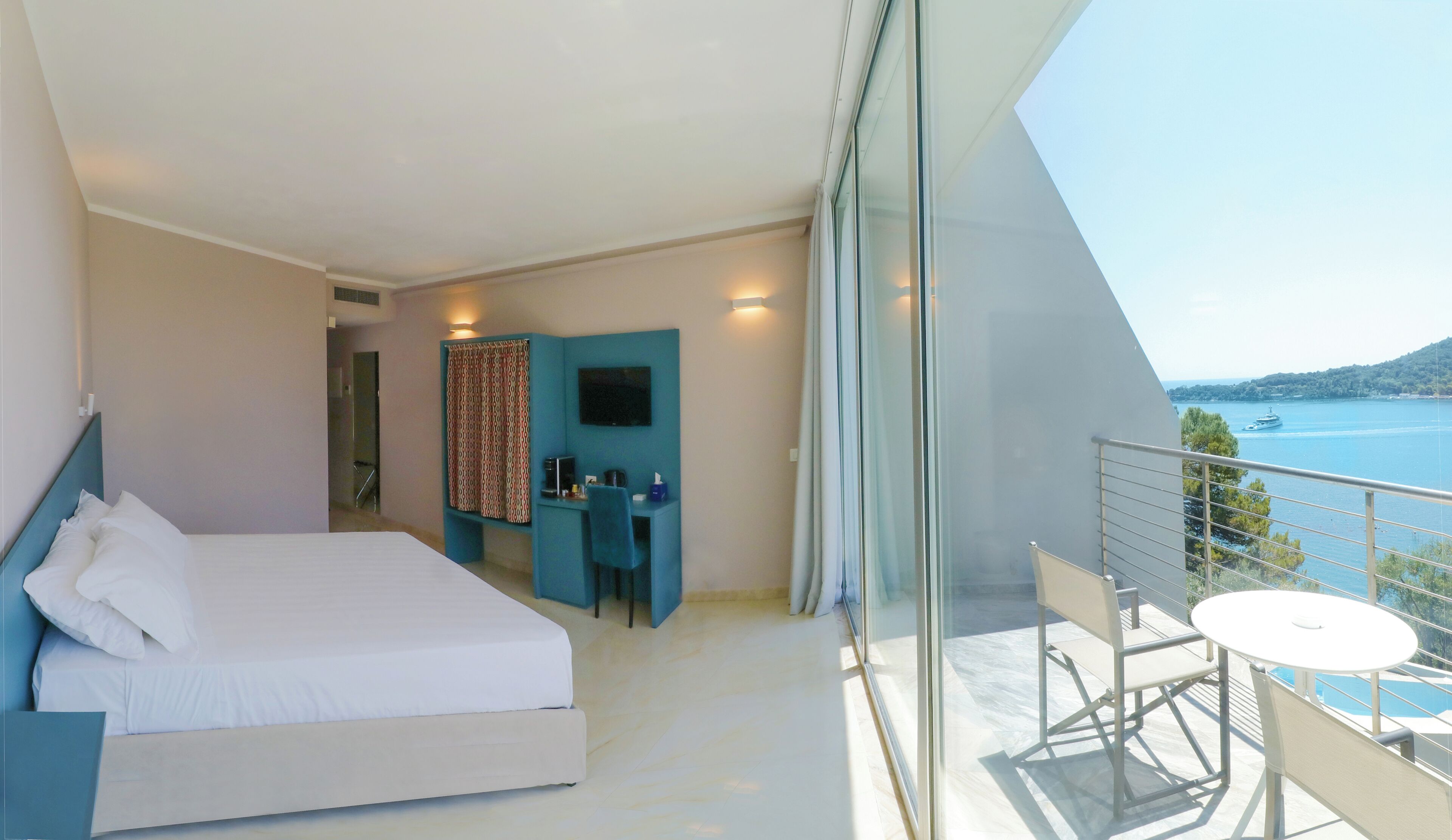 Una habitación de hotel moderna con balcón, cama, escritorio y televisor.