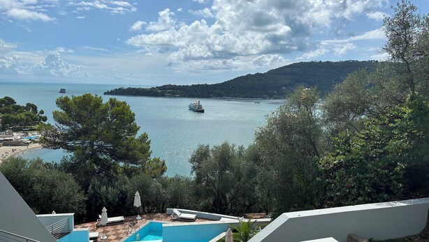 Un espace piscine offrant une vue sur la mer et sur un bateau au loin.