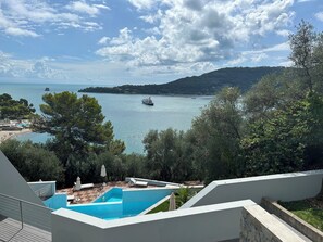 Un espace piscine offrant une vue sur la mer et sur un bateau au loin.