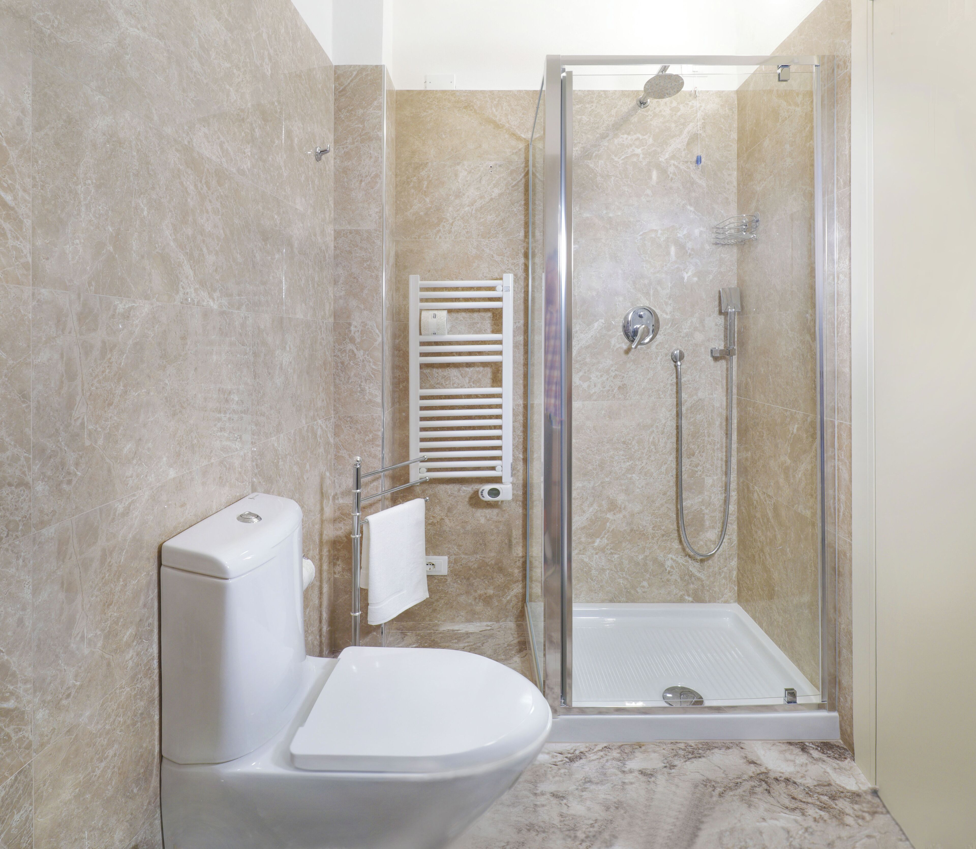 Un baño moderno con ducha de vidrio, inodoro y perchero para toallas.