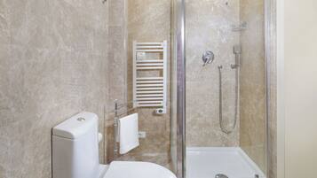 Un baño moderno con ducha de vidrio, inodoro y perchero para toallas.