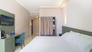 Une chambre d’hôtel avec un lit, un bureau, une chaise, une télévision et un rideau à motifs.