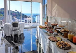 Una mesa de buffet con diferentes alimentos y vistas al mar a través de amplios ventanales.