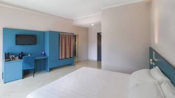 Una habitación de hotel con una cama grande, un escritorio con silla, un televisor y una cortina estampada.