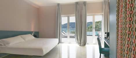 A hotel room with a bed, a desk, and a view of the outdoors.
