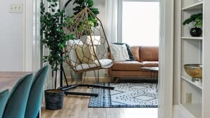 Una sala moderna con una silla colgante, un sofá y una zona de comedor con sillas.