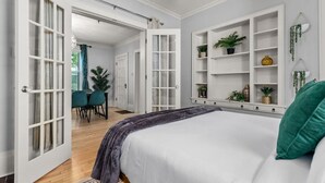 Un dormitorio con cama, escritorio, sillas y una estantería con plantas.