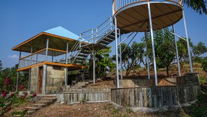 Una estructura de varios niveles con una escalera en espiral, un área cubierta y una torre cilíndrica.