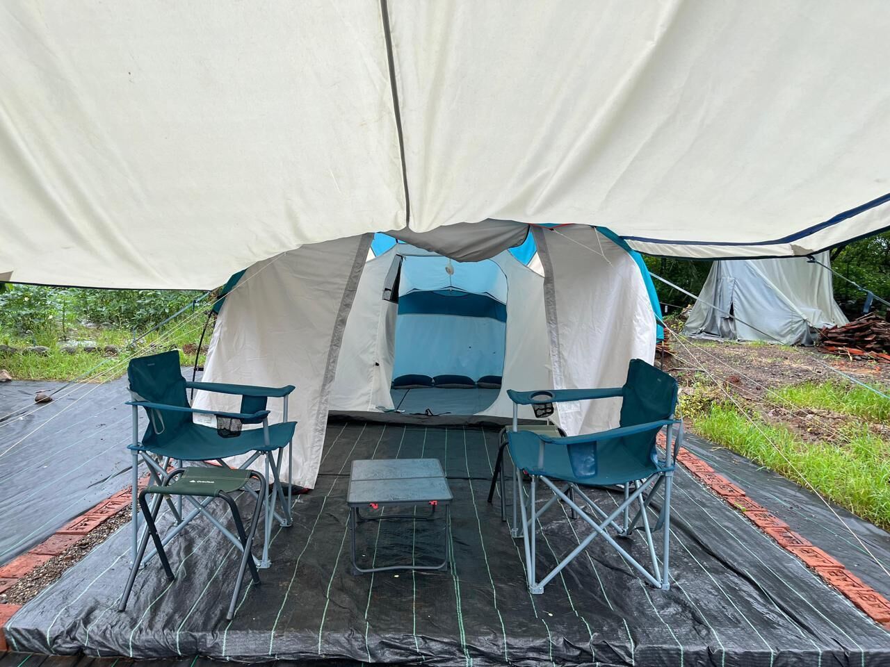 A tent with a table and two chairs in front.