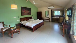 Un dormitorio con cama, muebles de madera, un cuadro y una pequeña cocina.