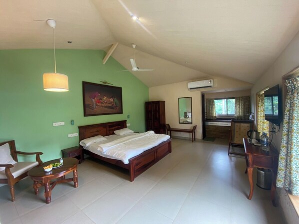 A bedroom with a bed, wooden furniture, a painting, and a kitchenette area. - The Riverstone Agro Farm (Panvel)