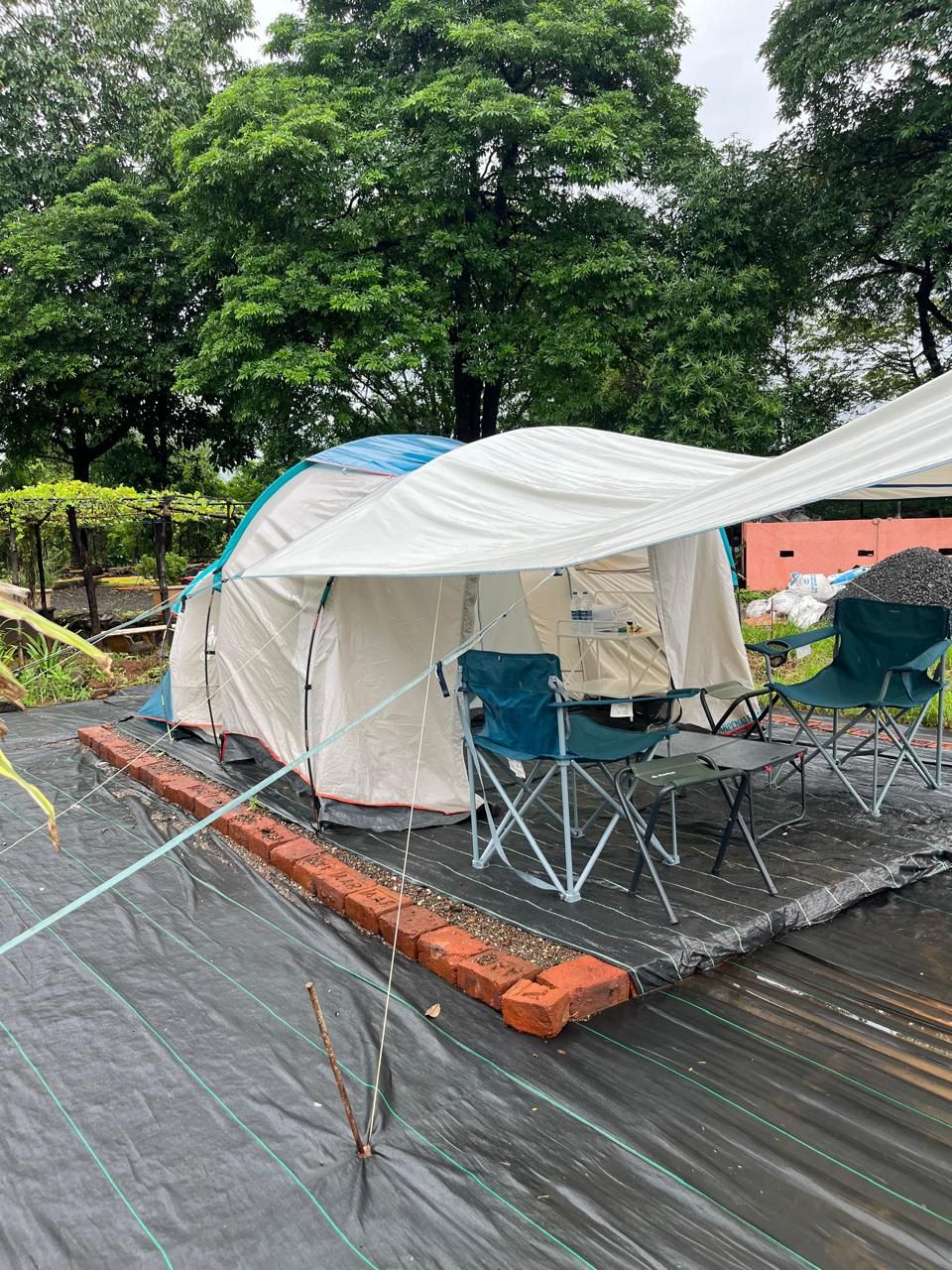 Una carpa montada en un área pavimentada, con una mesa y sillas cerca.