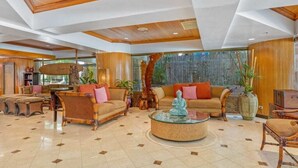 A spacious lobby with a high ceiling, wooden accents, and a central seating area with sofas and a round coffee table.