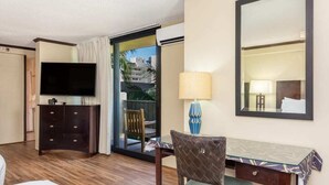 A hotel room with a bed, a desk with a chair, a television, a lamp, and a large mirror.