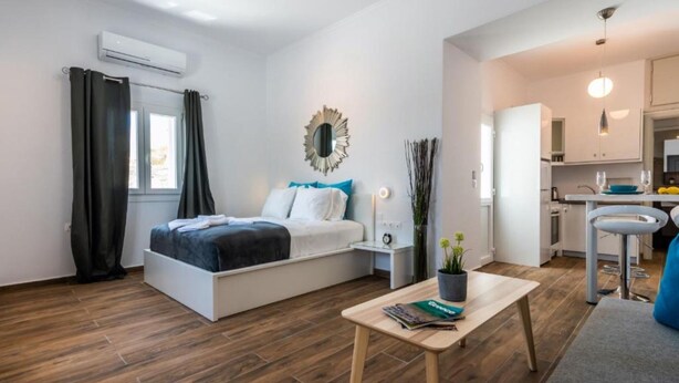 Ein modernes Schlafzimmer mit Bett, Nachttisch und Blick zur Küche.