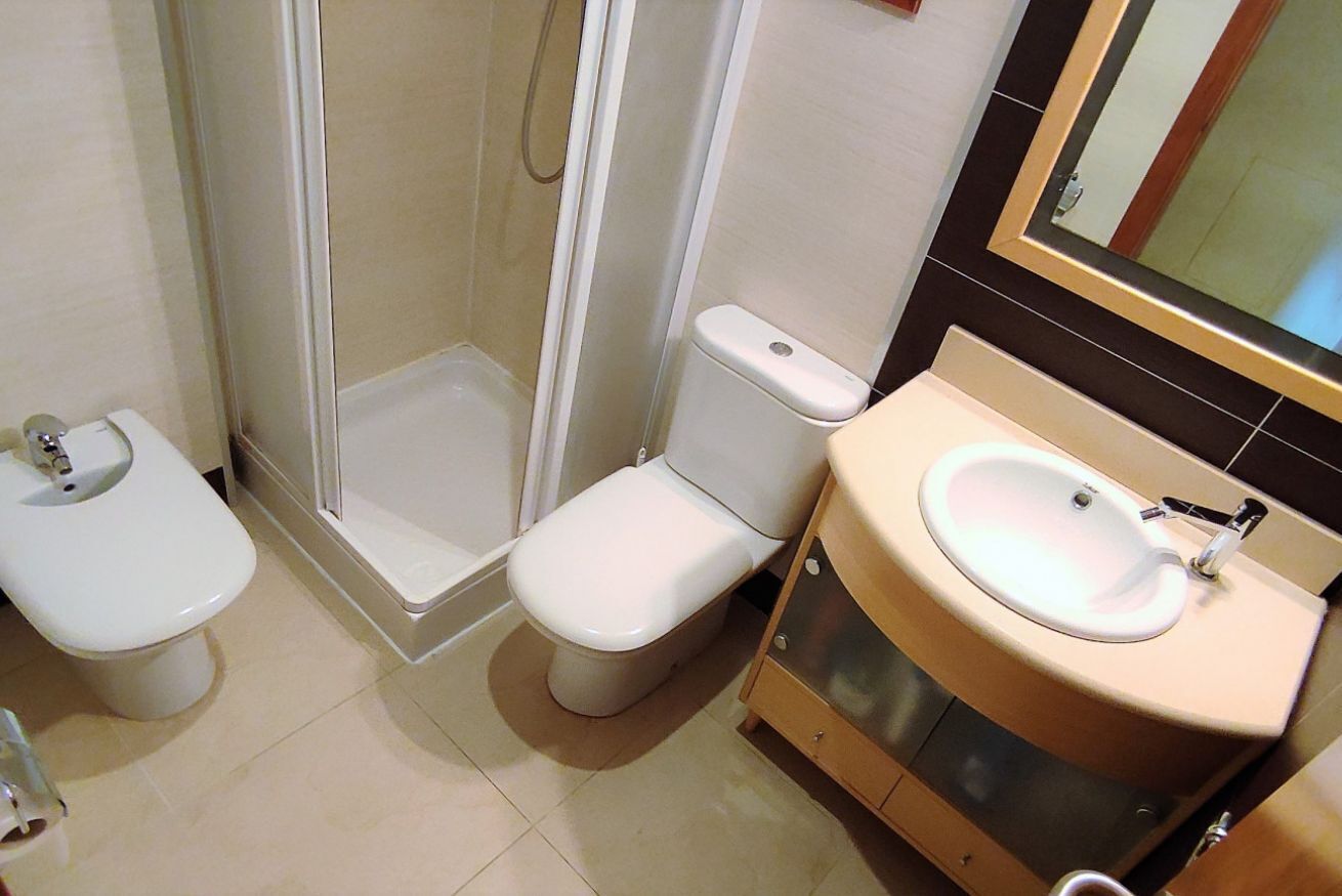 A bathroom with a toilet, a shower enclosure, and a sink with a mirror.