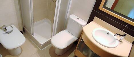 A bathroom with a toilet, a shower enclosure, and a sink with a mirror.
