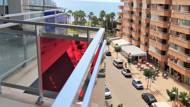 Un immeuble de grande hauteur doté de balcons donnant sur une rue et sur un plan d’eau.