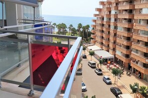 Un edificio alto con balcones que dan a una calle y una masa de agua.