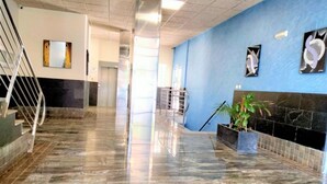 Un hall d’entrée spacieux avec un sol en marbre, un escalier, un mur d’accent bleu et une plante en pot.