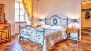Une chambre à coucher avec un lit en métal, une commode en bois, une table de chevet et une fenêtre avec des rideaux.