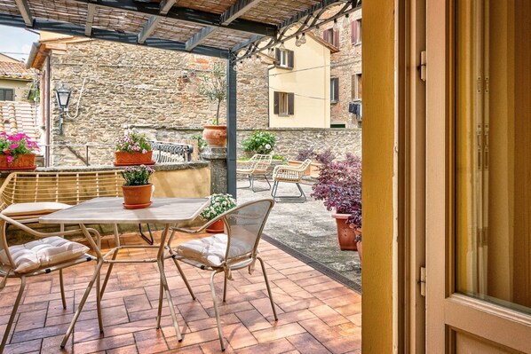 An outdoor patio with wicker furniture, potted plants, and a stone wall backdrop. - Il Giardino di Adele - private garden with view, downtown Cortona (Cortona)