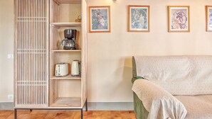 A room with a wooden cabinet, a green sofa, and four framed artworks on the wall. - Il Giardino di Adele - private garden with view, downtown Cortona (Cortona)