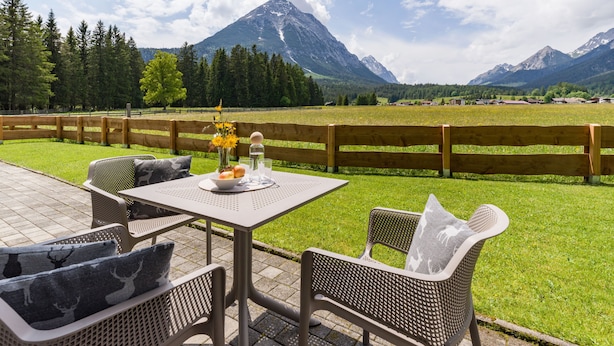 Een terras met een tafel en stoelen, een houten omheining en uitzicht op een berg.