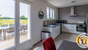 A modern kitchen with a large island, a dining area with a view, and a patio with outdoor seating.