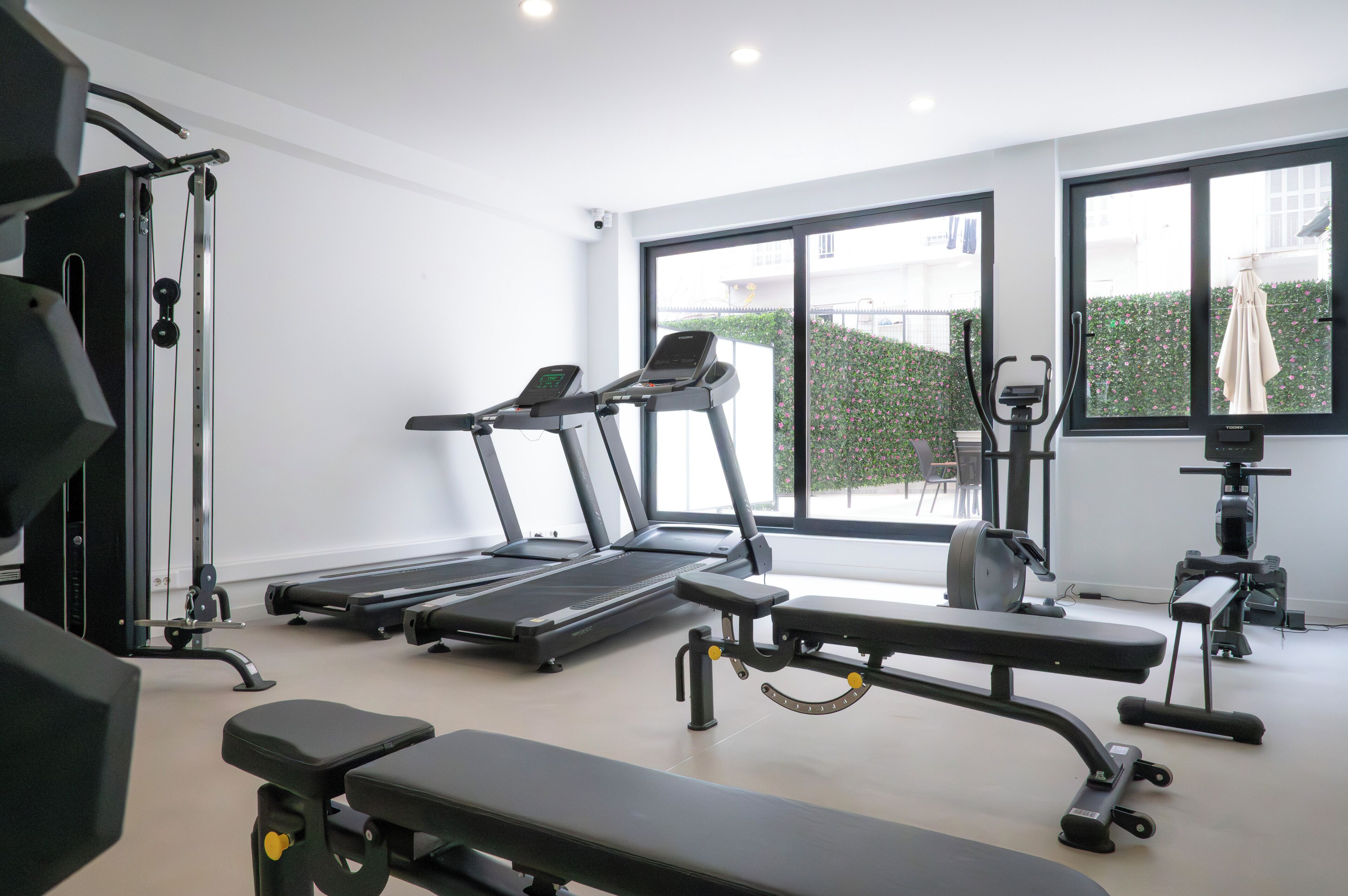 Une salle de sport équipée de tapis de course, d’un banc et d’appareils de musculation.