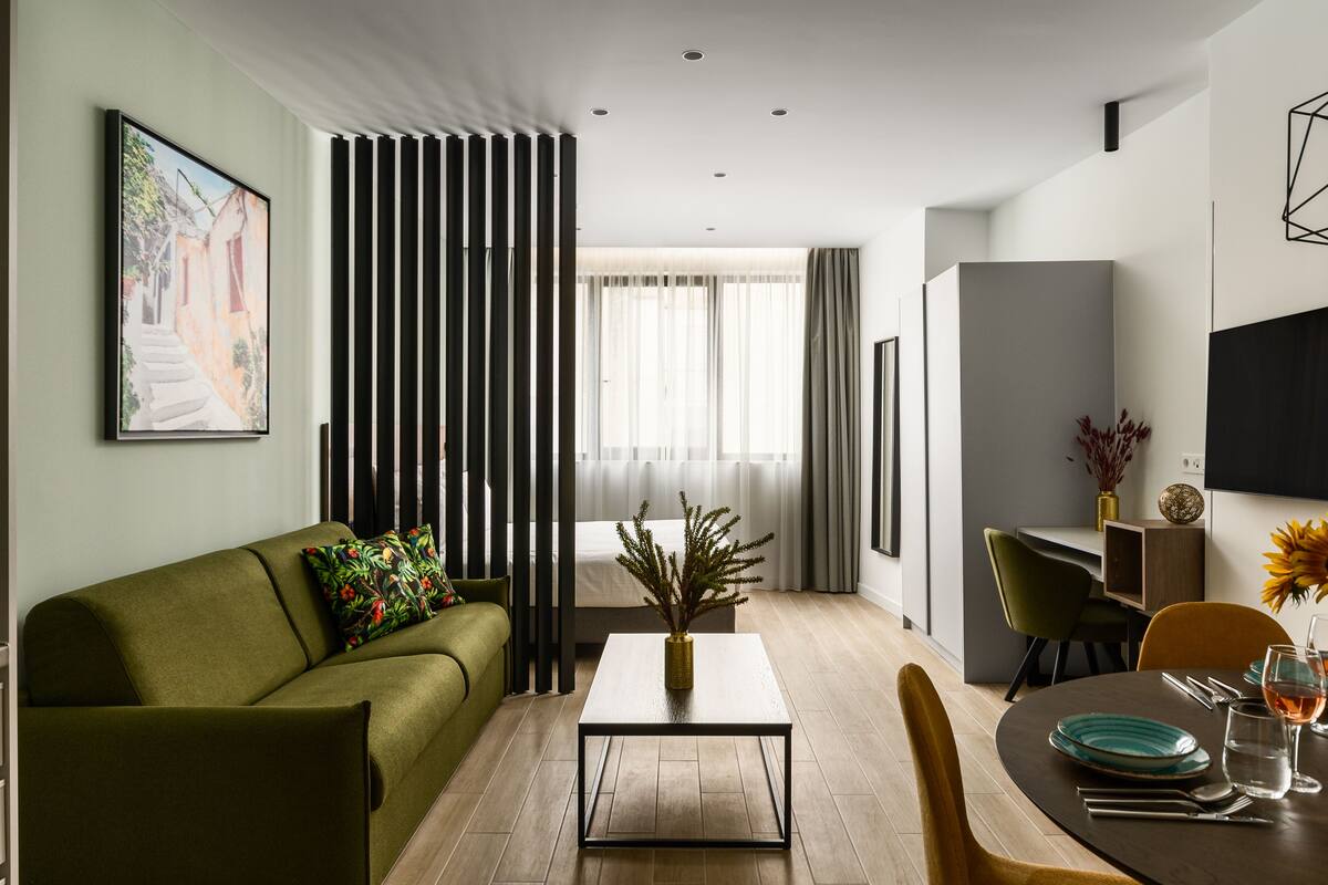 Een moderne woonkamer met een bank, een salontafel, en een eethoek met stoelen en een tafel gedekt voor twee personen.