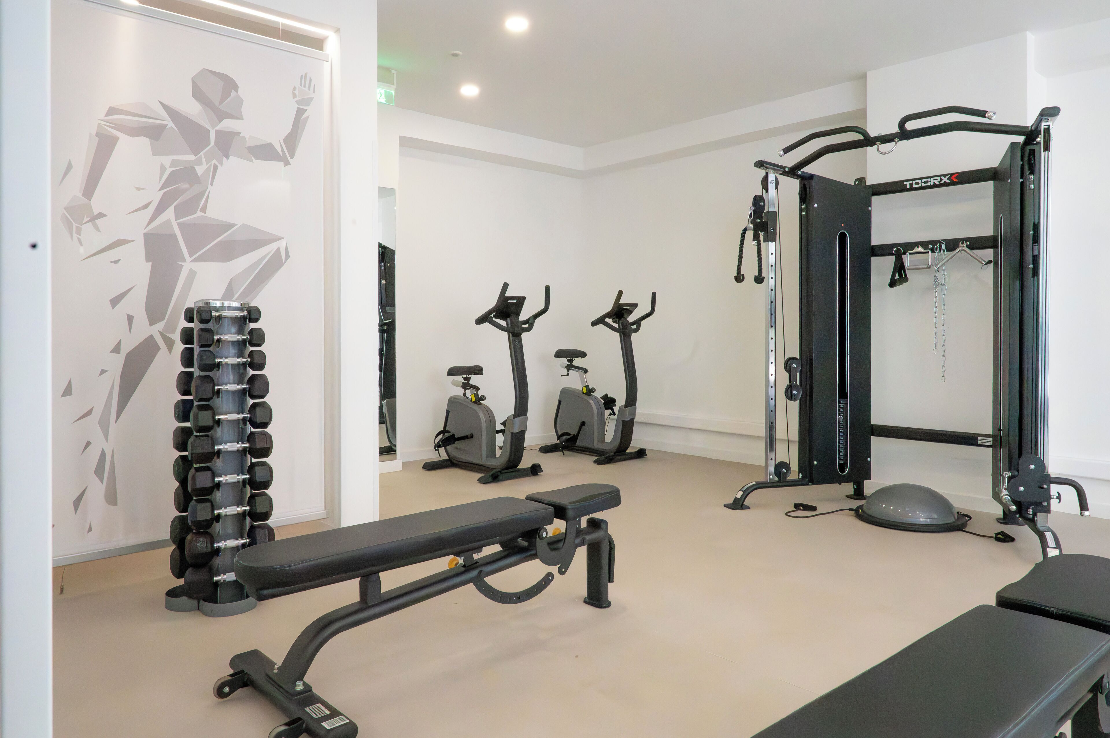 A gym with exercise equipment including dumbbells, treadmills, and a squat rack.