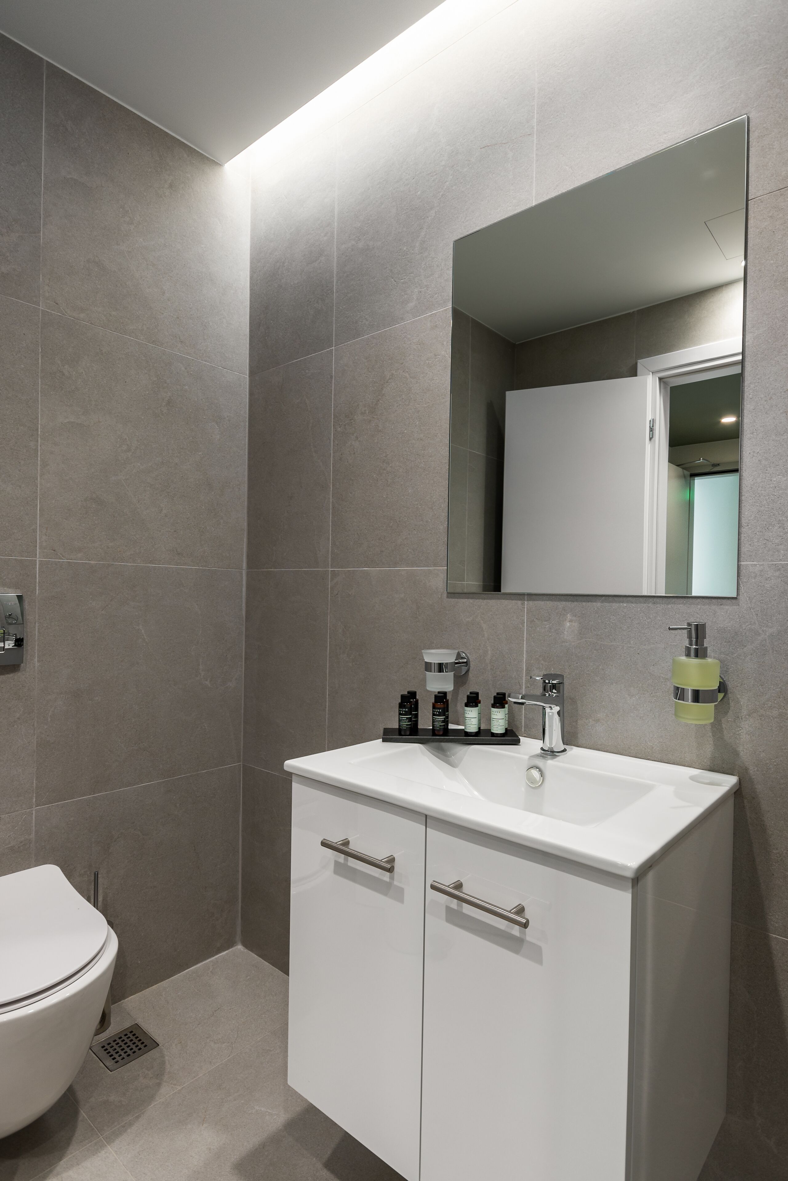 Une salle de bain moderne avec un lavabo blanc, un miroir et des toilettes.