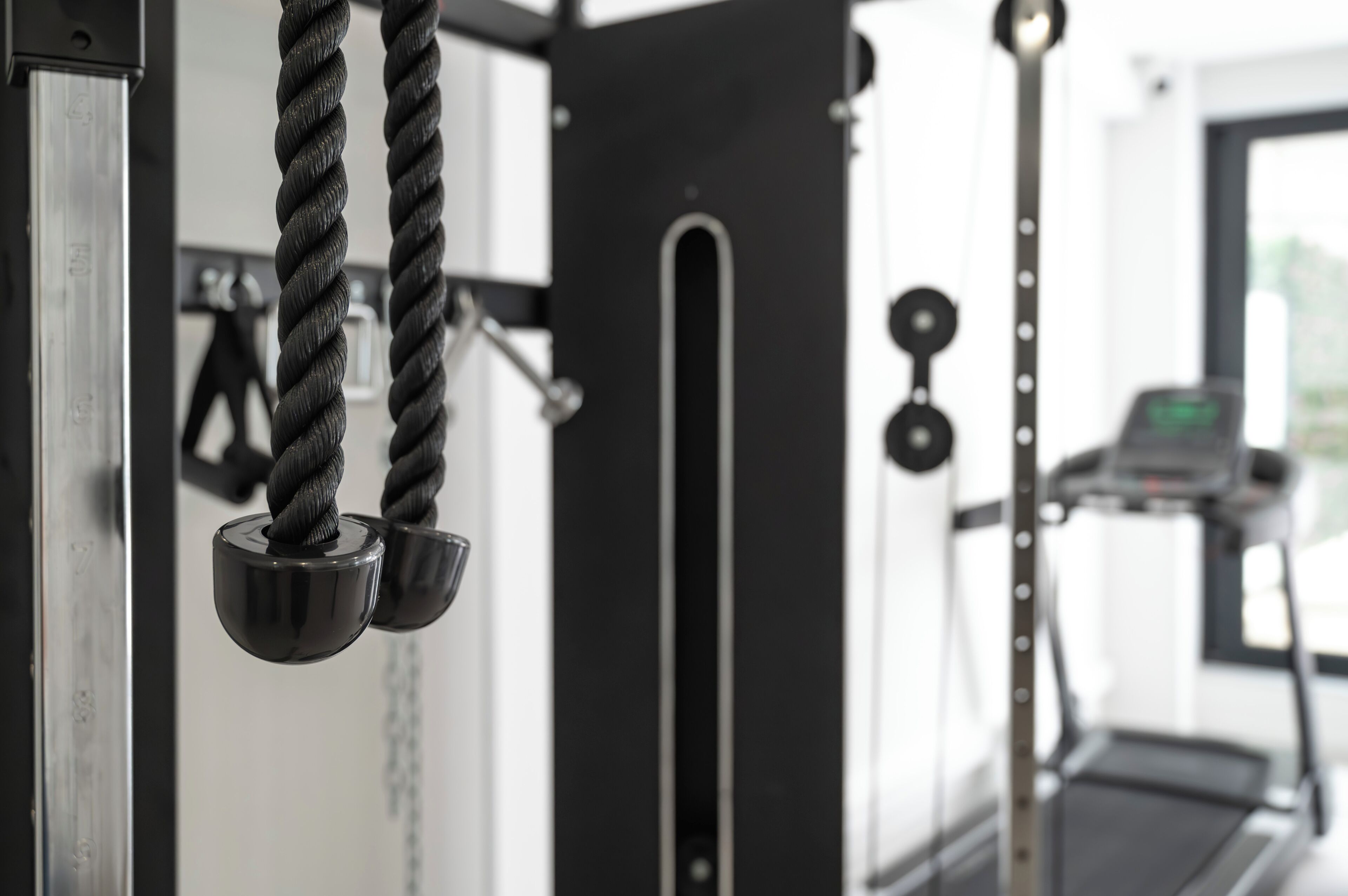 Een fitnessruimte met trainingsapparatuur, waaronder een touw, gewichten en een loopband.