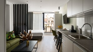 Eine moderne Küche mit Einbauofen, ein Essbereich mit Tisch und Stühlen und ein Sofa mit farbigem Kissen.