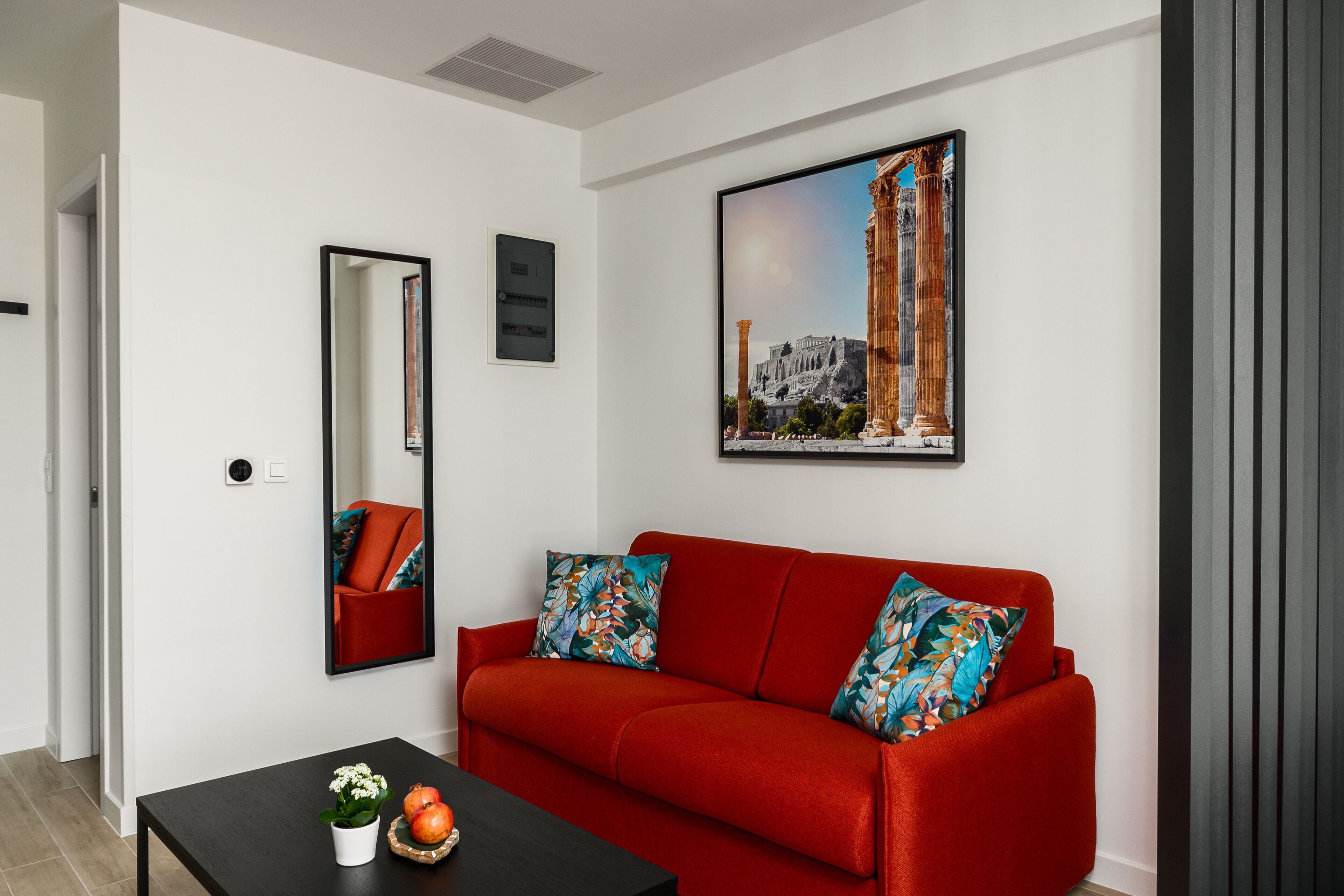 A modern living room with a red sofa, a black coffee table, and a cityscape painting.