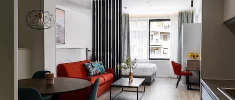 A modern living room with a red sofa, a coffee table, and a dining area with chairs.
