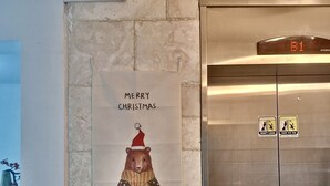 A poster with a bear wearing a Santa hat and a Christmas sweater, and a digital elevator display showing 'B1'. - King's garden -Ikseon Stay (Seoul)