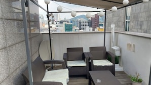 A balcony with wicker furniture, a satellite dish, and a city view. - King's garden -Ikseon Stay (Seoul)