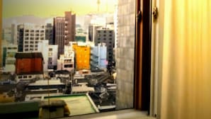 A cityscape view from a window with a curtain partially drawn. - King's garden -Ikseon Stay (Seoul)