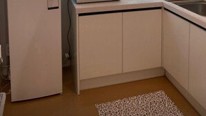 A compact kitchen with a refrigerator, microwave, and sink. There is a window with sheer curtains and a pendant light above the counter. - King's garden -Ikseon Stay (Seoul)