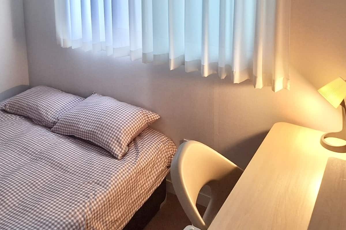 Une chambre d’hôtel avec un lit, un bureau et une chaise.