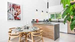 Une cuisine moderne dotée d’un îlot central, de chaises en bois et d’une table à manger pour quatre personnes.