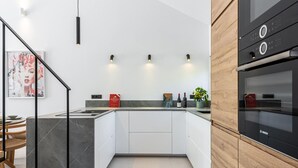 Une cuisine moderne avec un four Bosch noir, des armoires blanches et un îlot en marbre.