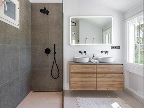 A modern bathroom with a walk-in shower, two sinks, a large mirror, and wooden cabinetry. - Beautifully Modern Duplex with Pool, Near Beach and Puerto Banus (Marbella)