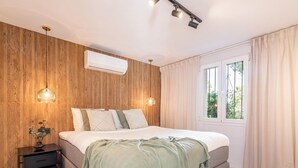 Une chambre avec un mur en bois, un lit recouvert d’une couverture verte, des tables de chevet et une fenêtre avec des rideaux.