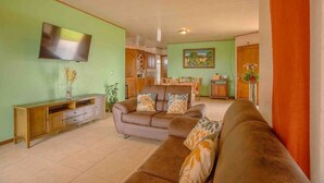 Una sala de estar con sofá, televisor y mueble de madera.
