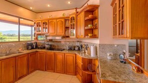 Una cocina amplia con armarios de madera, encimeras de granito y vistas al exterior.