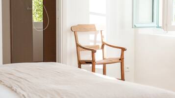 A bedroom with a bed, a wooden chair, a window, and a door.
