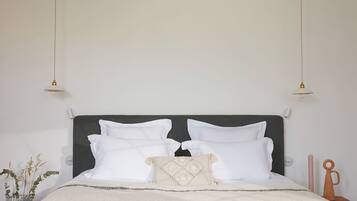 A bed with white bedding, a dark headboard, and two pendant lights.